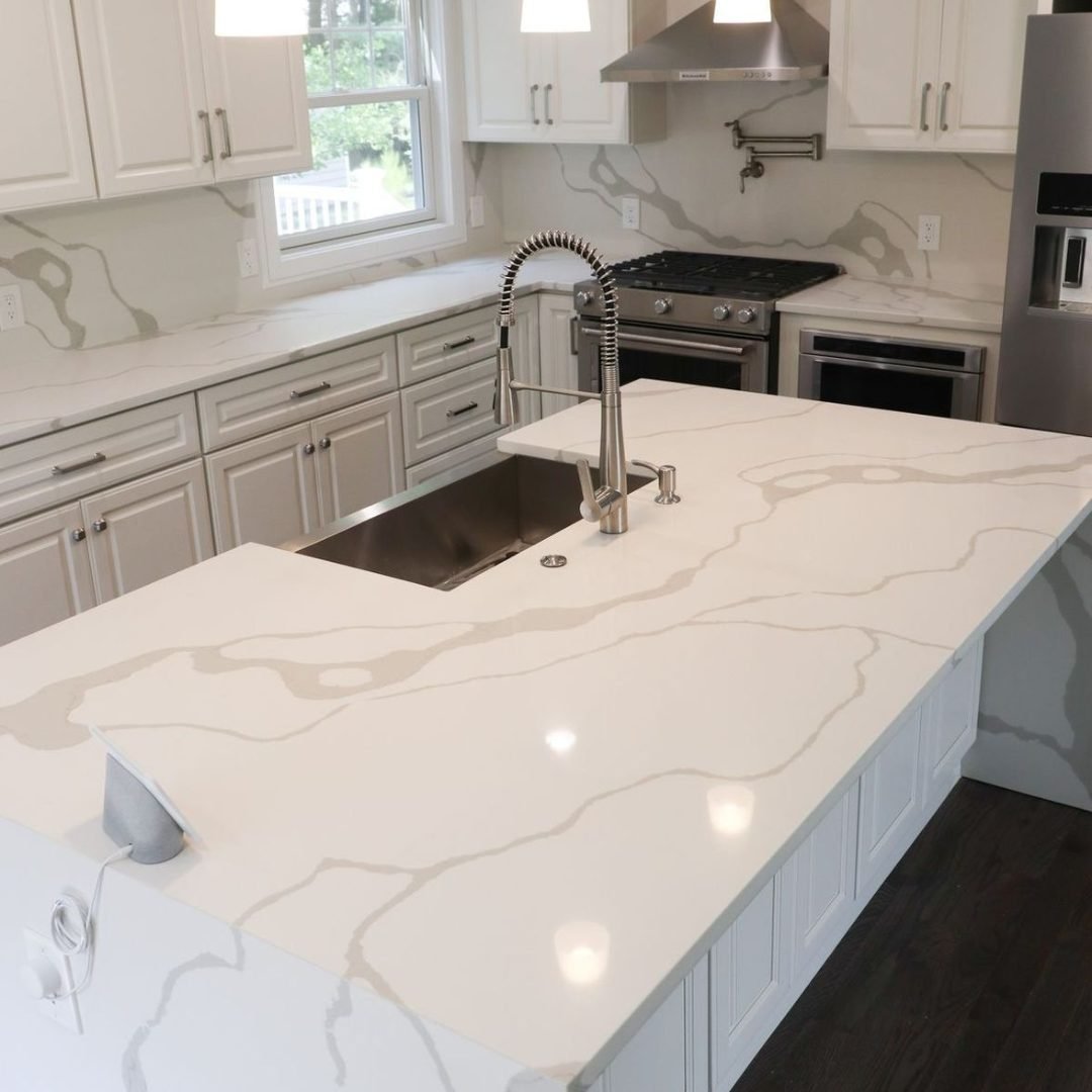 Dapur modern dengan meja pulau bermotif marmer putih dan kabinet putih